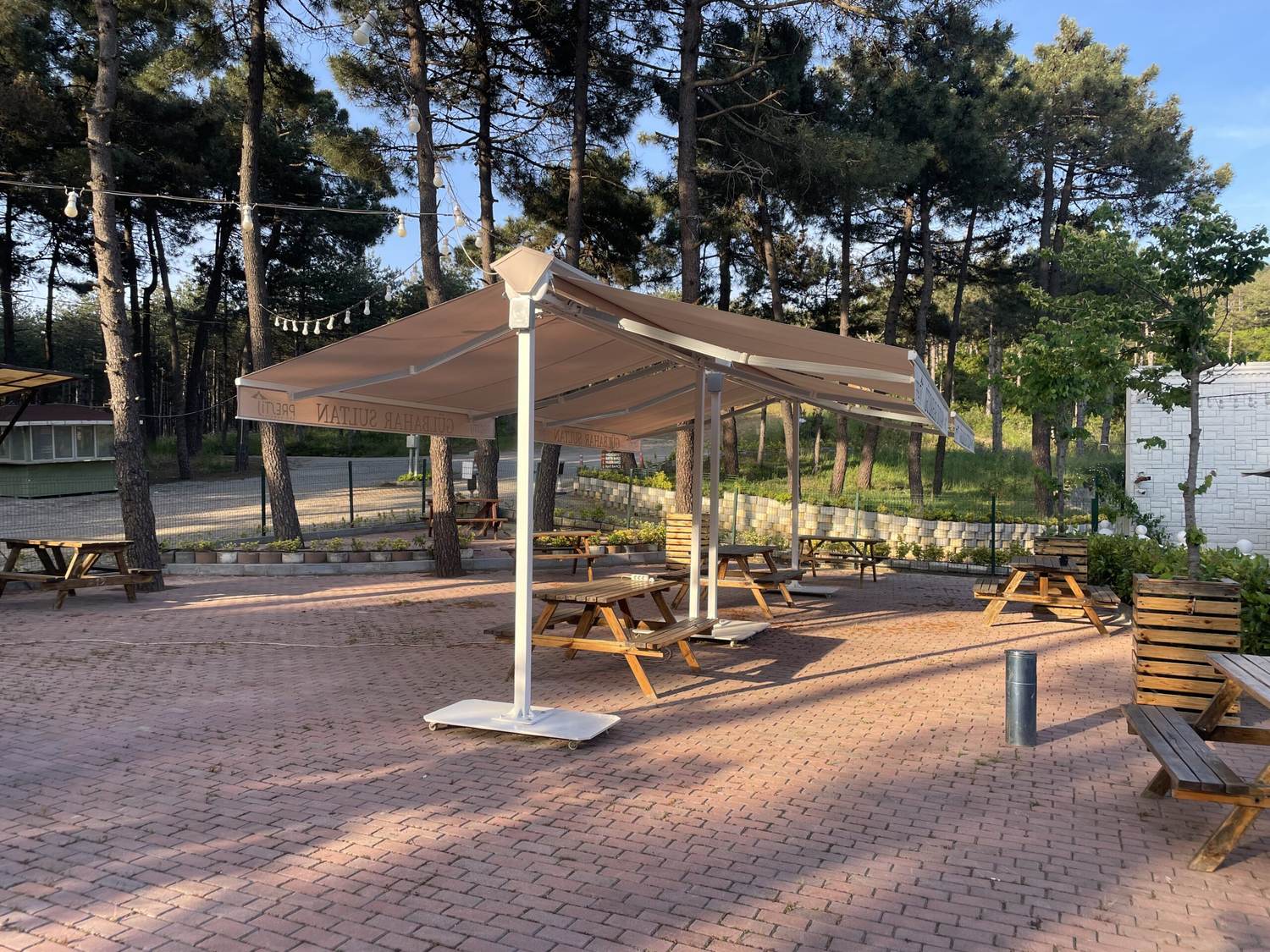 Orman kenarındaki terasta kare dev şemsiye